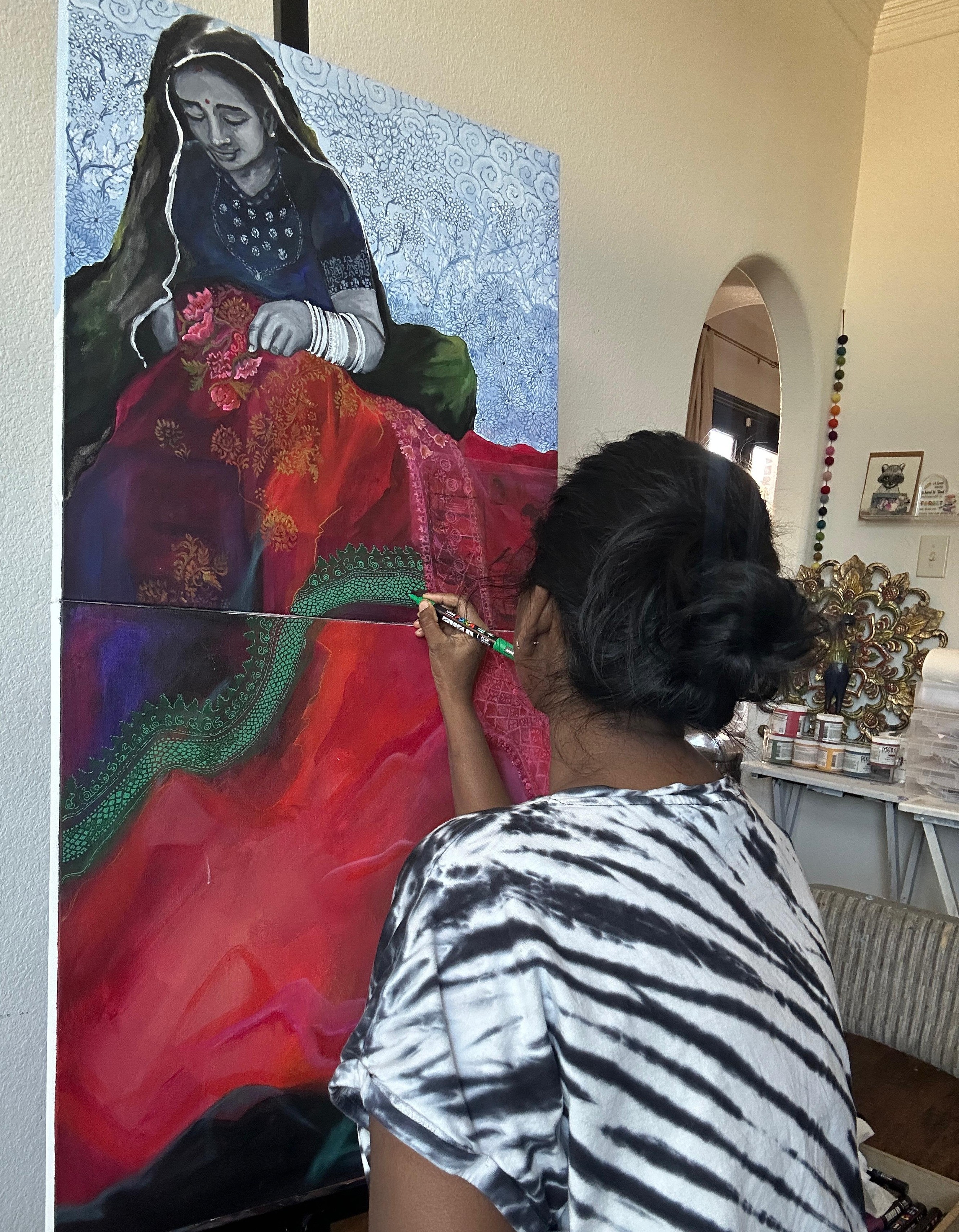 Bharathi painting a portrait of a woman in traditional dress on canvas